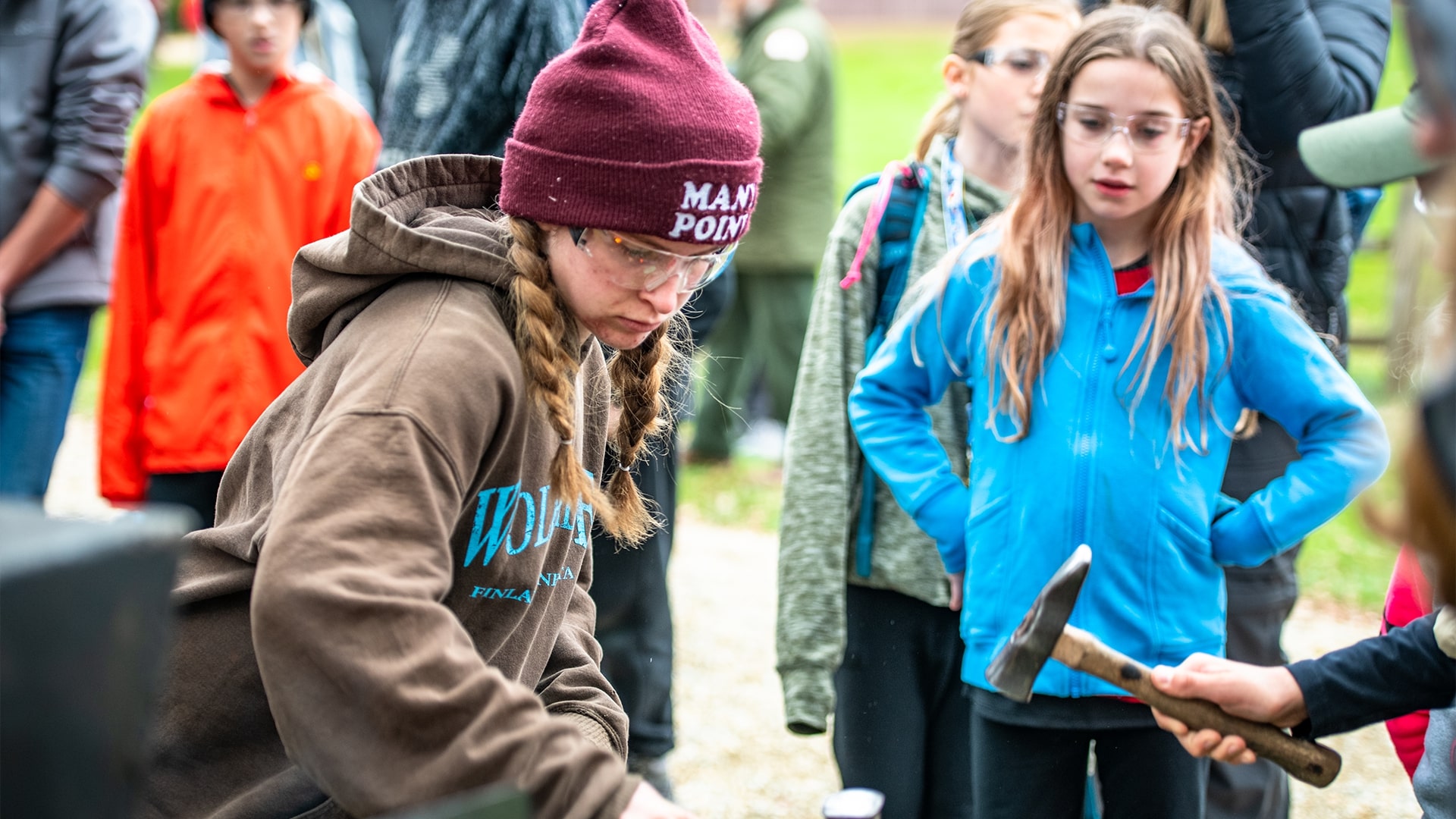 A female Scout wearing a Many Point hat and sweater working on a blacksmithing project at the Fall Camporee