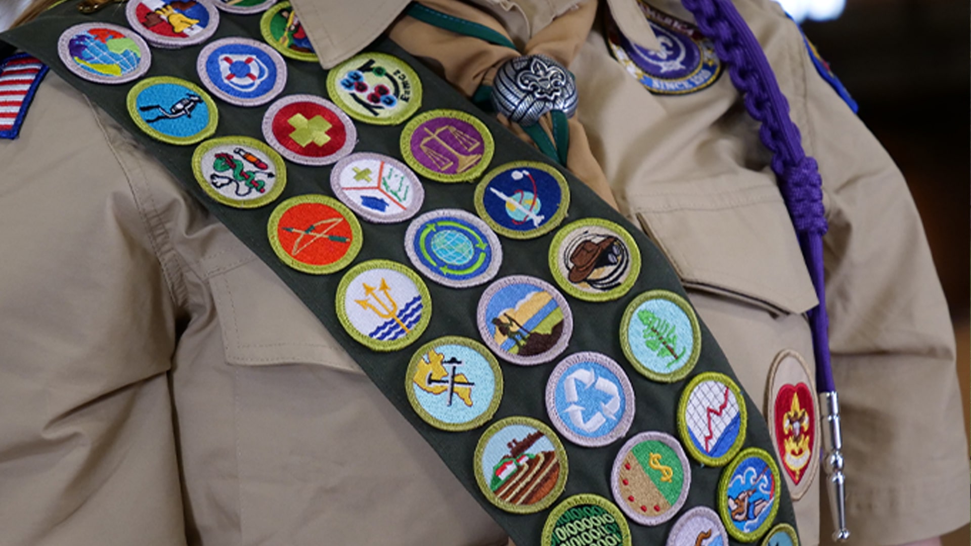 A close-up view of a Scout's merit badges sewn onto their sash