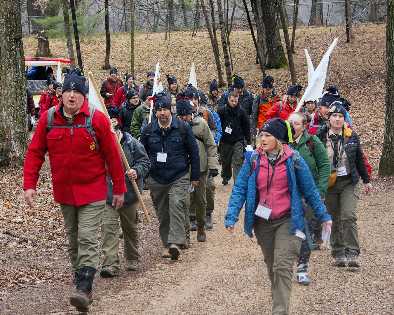 A Wood Badge course leader leads a hike for a a class. Twenty-five or so participants are following in two lines.