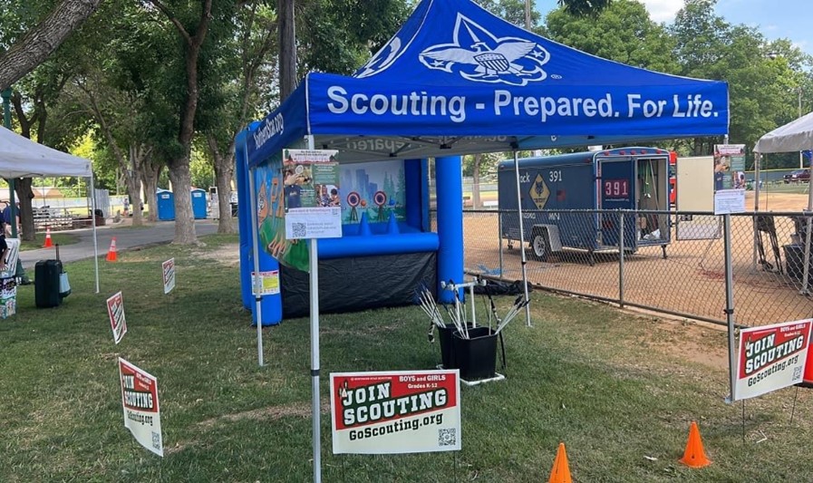 A mobile archery booth with "Join Scouting" yard signs scattered around A mobile archery booth with "Join Scouting" yard signs scattered around