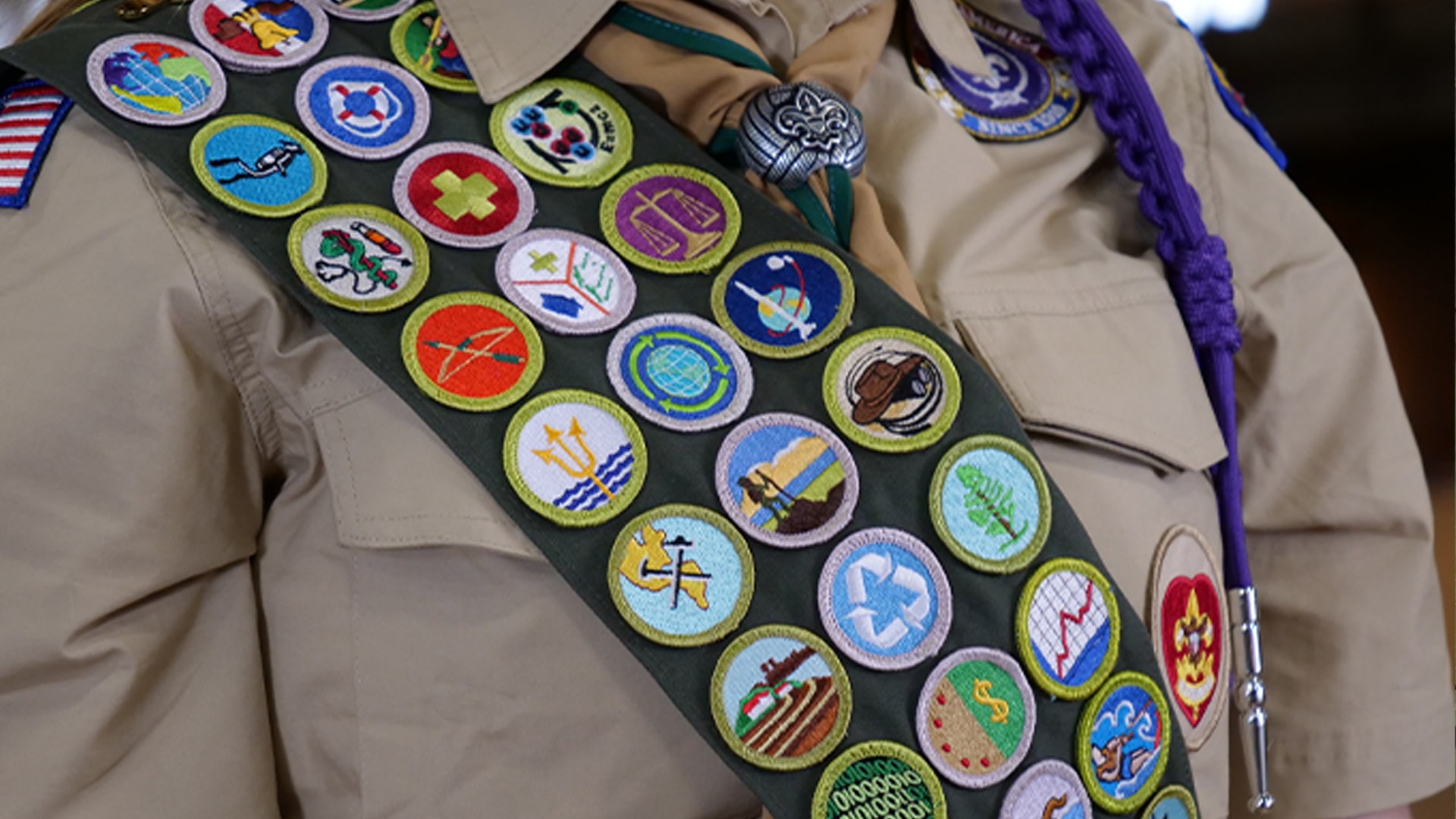 A close-up view of a Scout's merit badges sewn onto their sash A close-up view of a Scout's merit badges sewn onto their sash