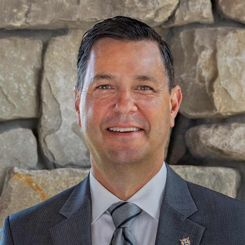 John Andrews smiling while wearing a suit.