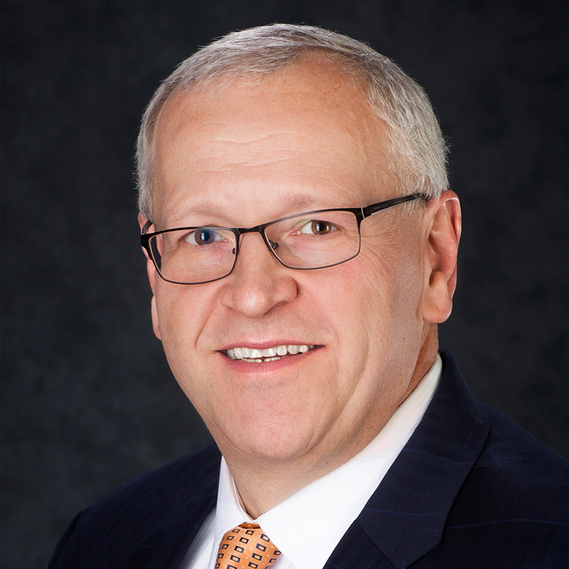 John G Patterson smiling while wearing a suit.